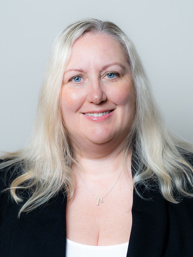 A woman is wearing a black jacket and a black and white shirt.