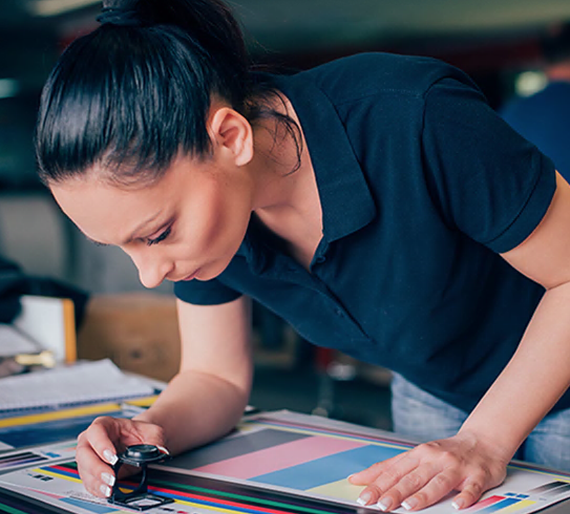 A woman in a blue shirt is working on a printing machine.