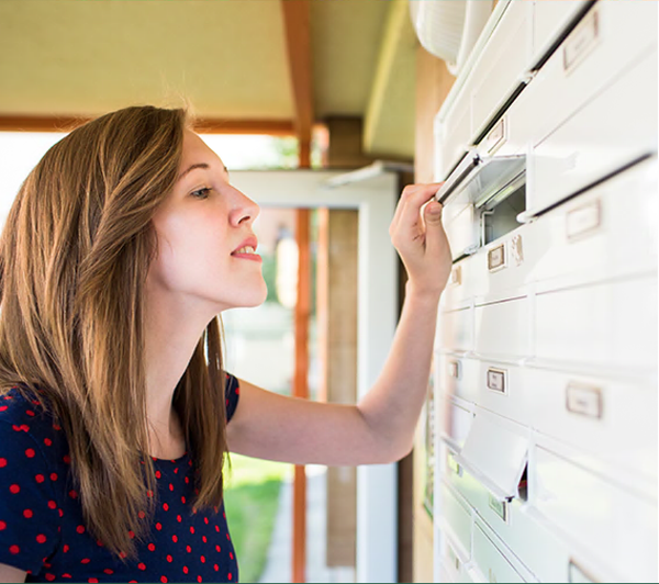 A woman is putting a letter in a mailbox