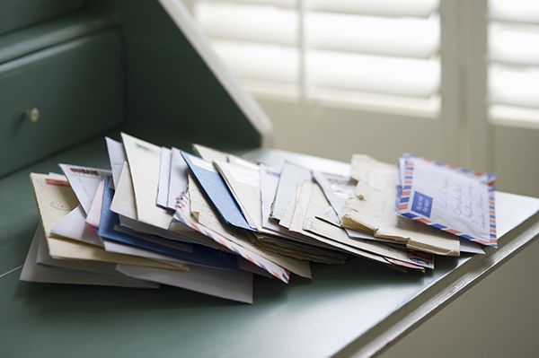 A pile of letters and envelopes on a desk