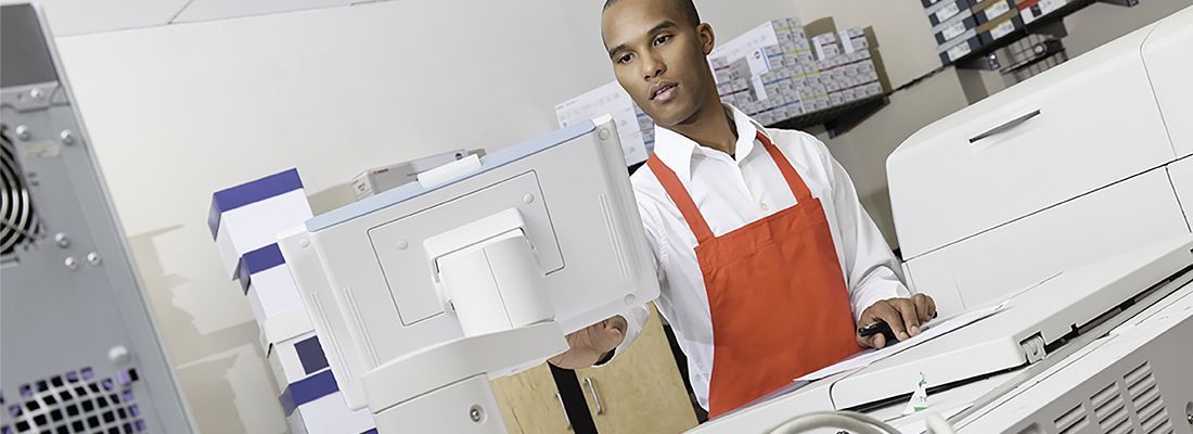 A man in a red apron is working on a computer