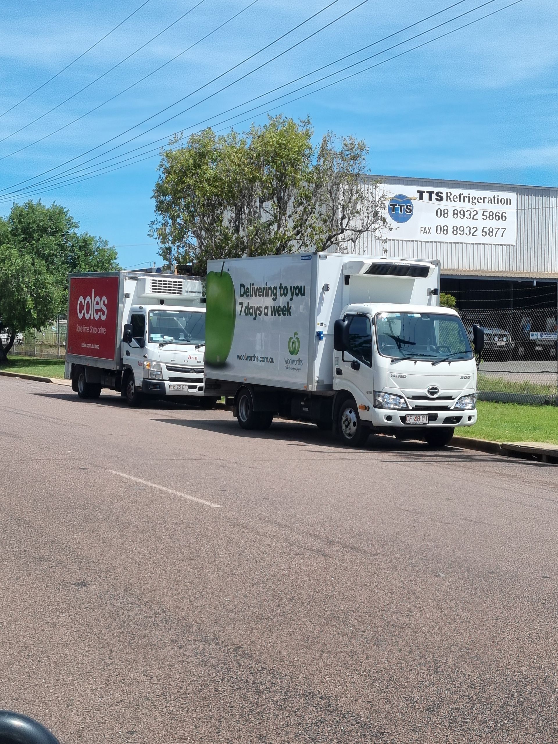 Three white refrigerated delivery trucks parked on a road in front of a building with blue sky in the background — TTS Refrigeration in Pinelands, NT