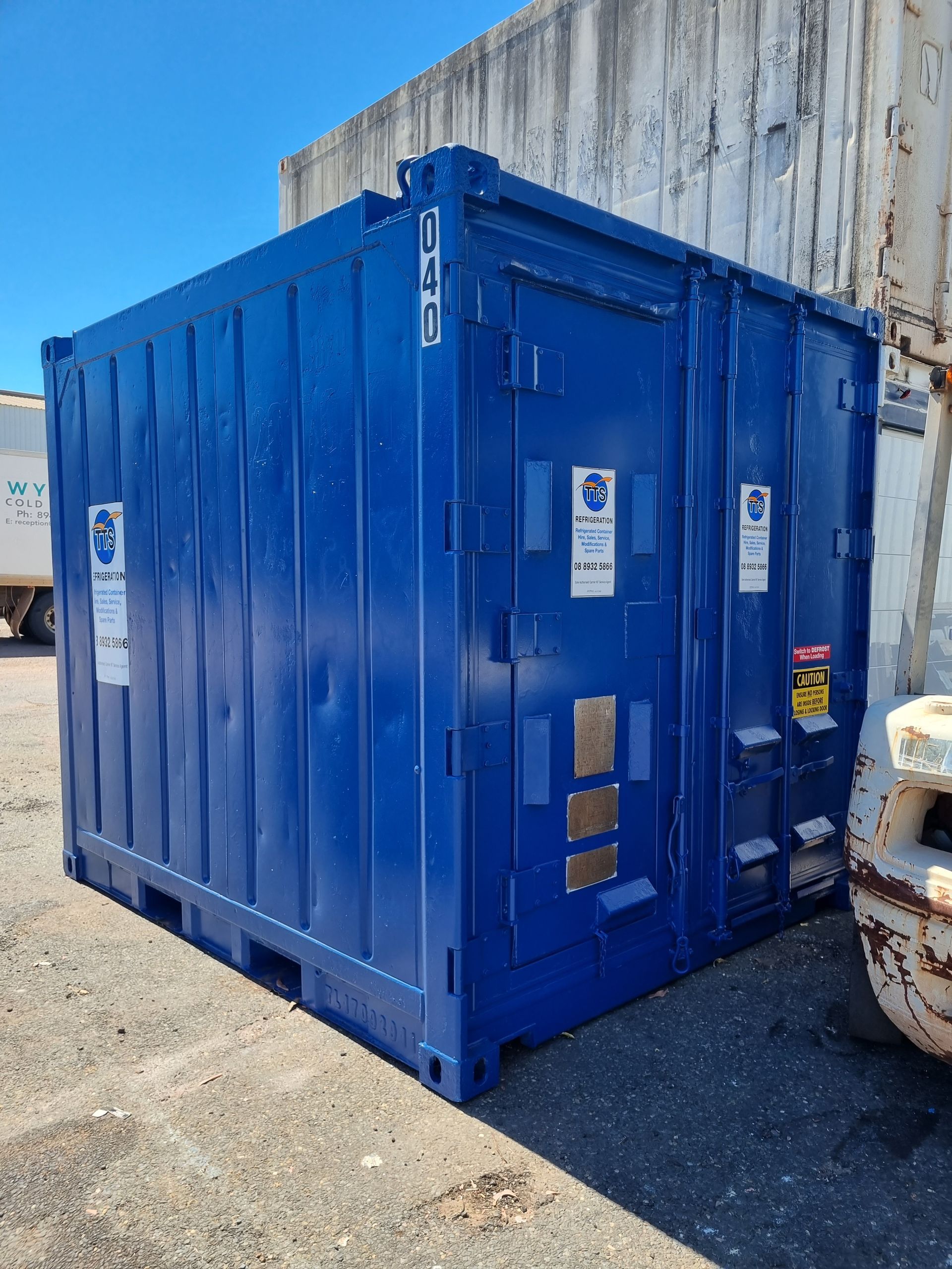 Blue shipping container on a concrete surface against a white wall — TTS Refrigeration in Pinelands, NT