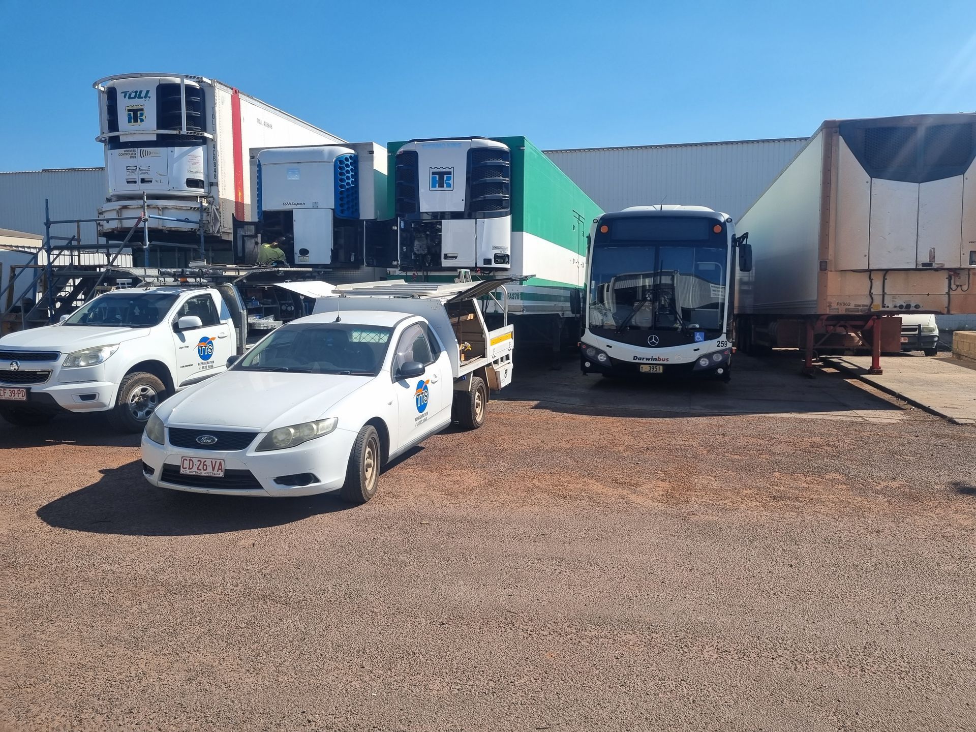 White vehicles and trailers parked in a lot; a bus is present — TTS Refrigeration in Pinelands, NT