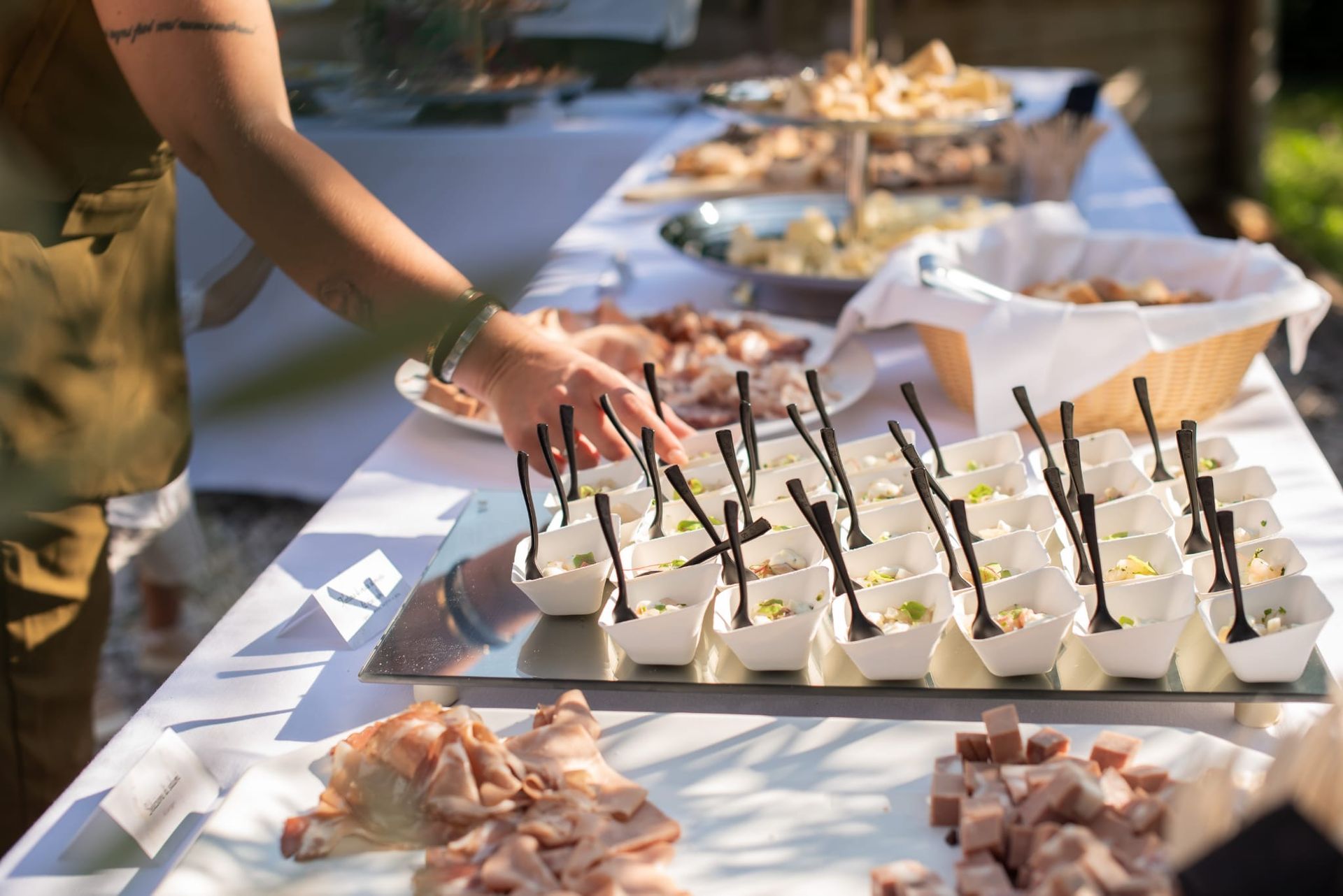 Disposizione a mano di coppette da dessert su un tavolo da buffet bianco all'aperto, con altri antipasti nelle vicinanze.