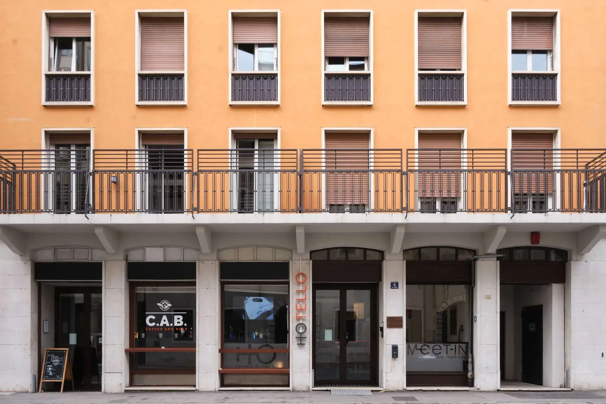 Hotello Trieste con balconi e colonne bianche al piano terra.