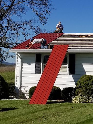 Two men are working on the roof of a white house