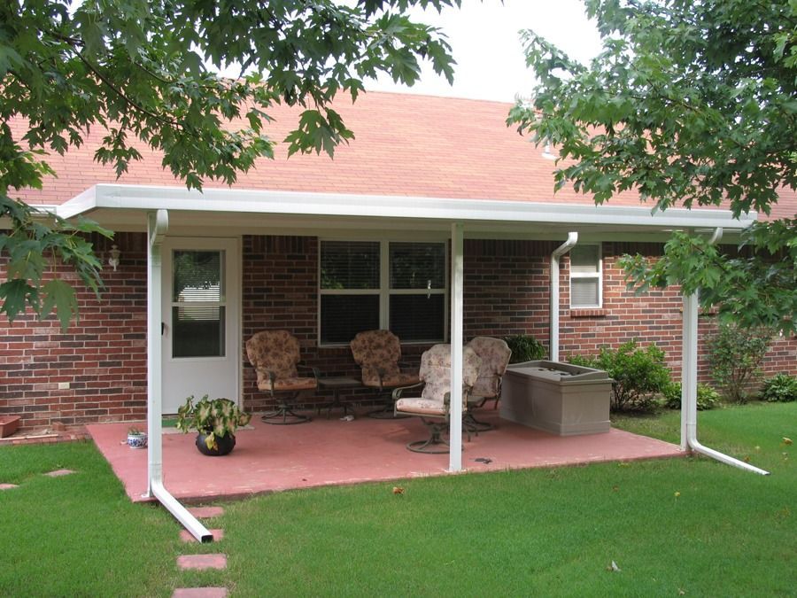 A brick house with a porch with chairs underneath it