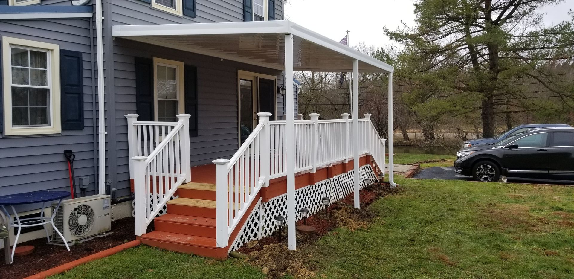 A house with a porch and a car parked in front of it.