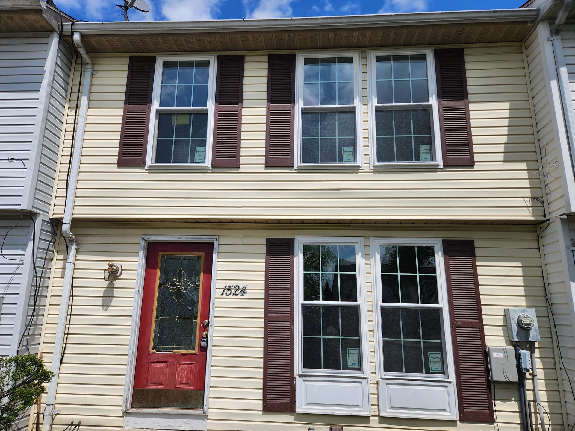 The front of a house with a red door and brown shutters
