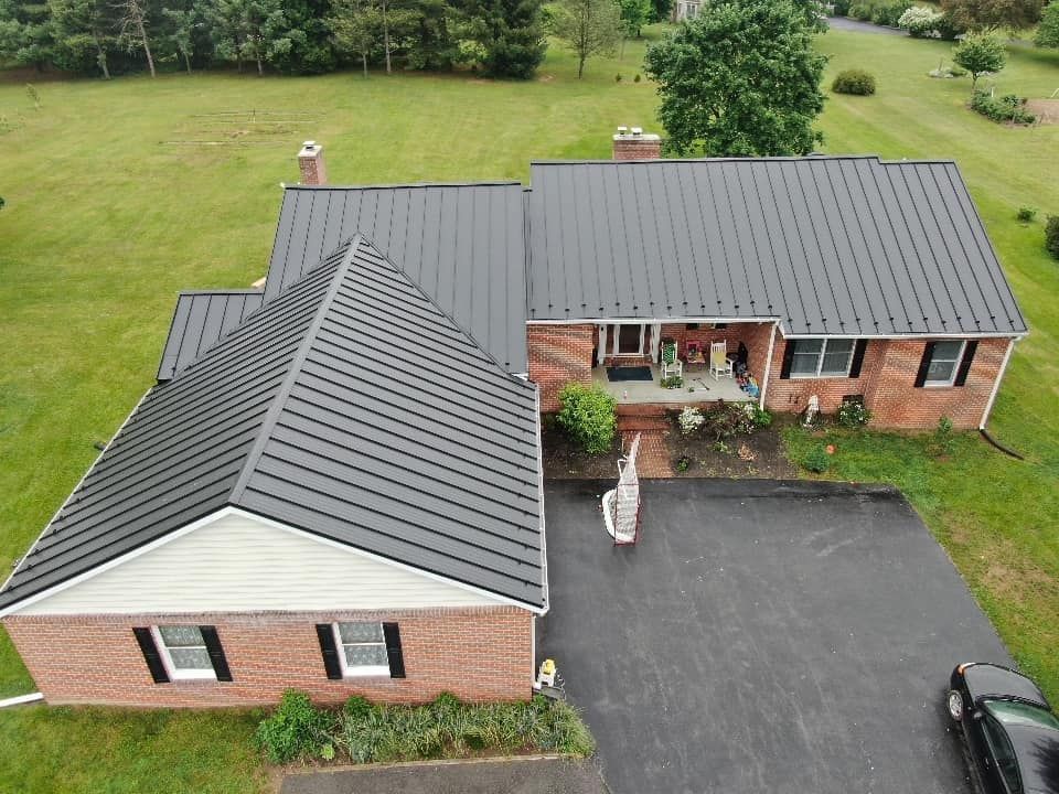 An aerial view of a brick house with a black roof and a black truck parked in front of it.