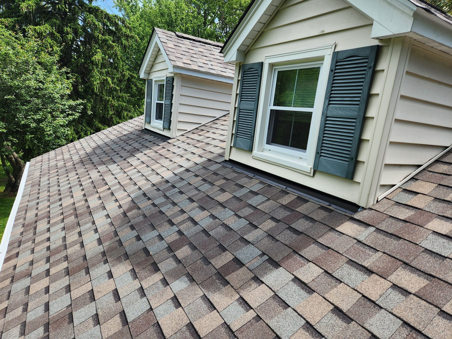 The roof of a house with a window and shutters on it.