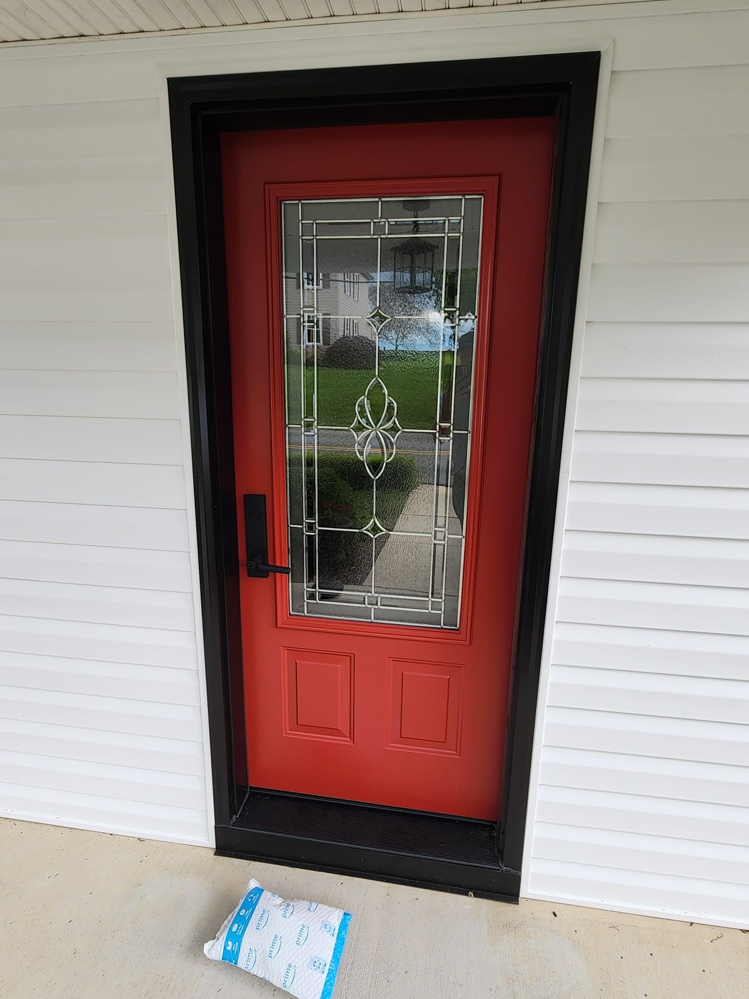 A red door with a black trim is on a white house.