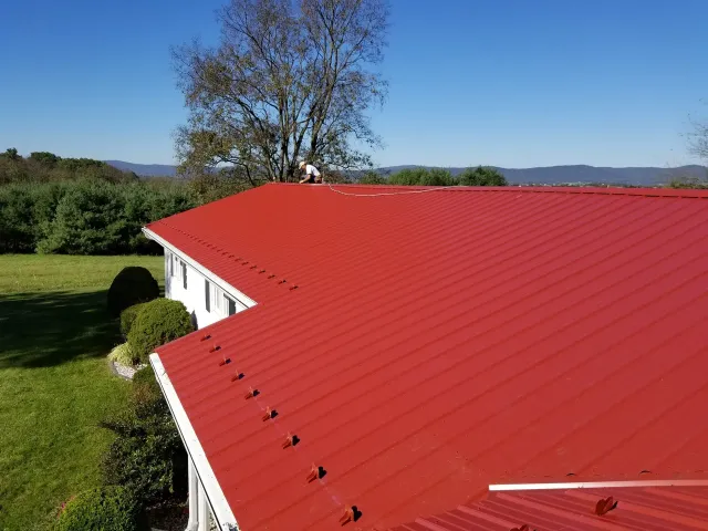A man is standing on top of a red roof.