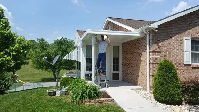 A man is standing on a ladder on the porch of a house.