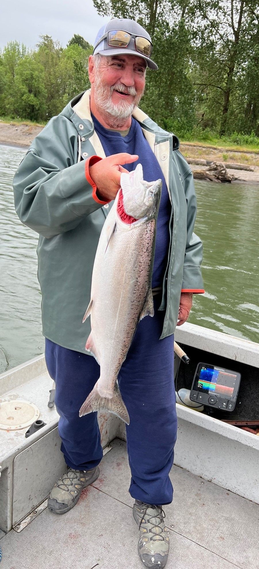 A man is standing on a boat holding a large fish.