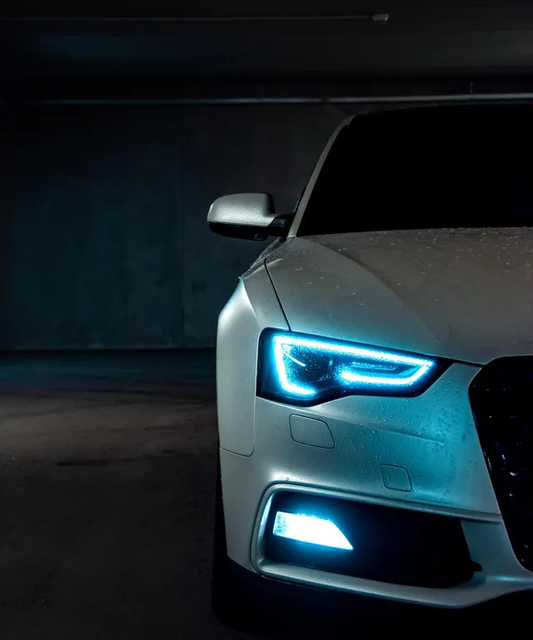 Car with its headlights on, front view of the passendger side only