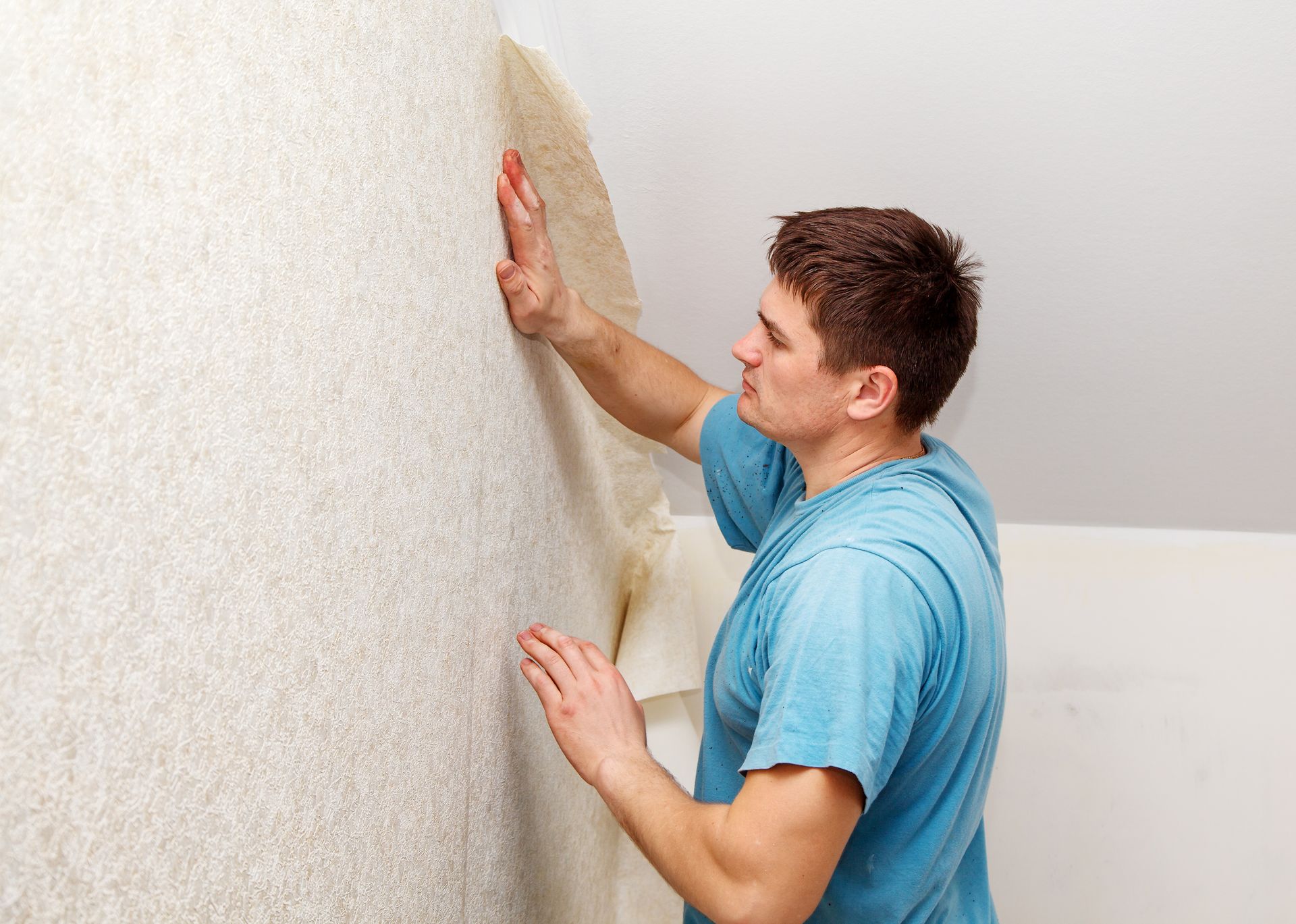 Tradesperson hanging patterned wallpaper on an accent wall in a Virginia living room