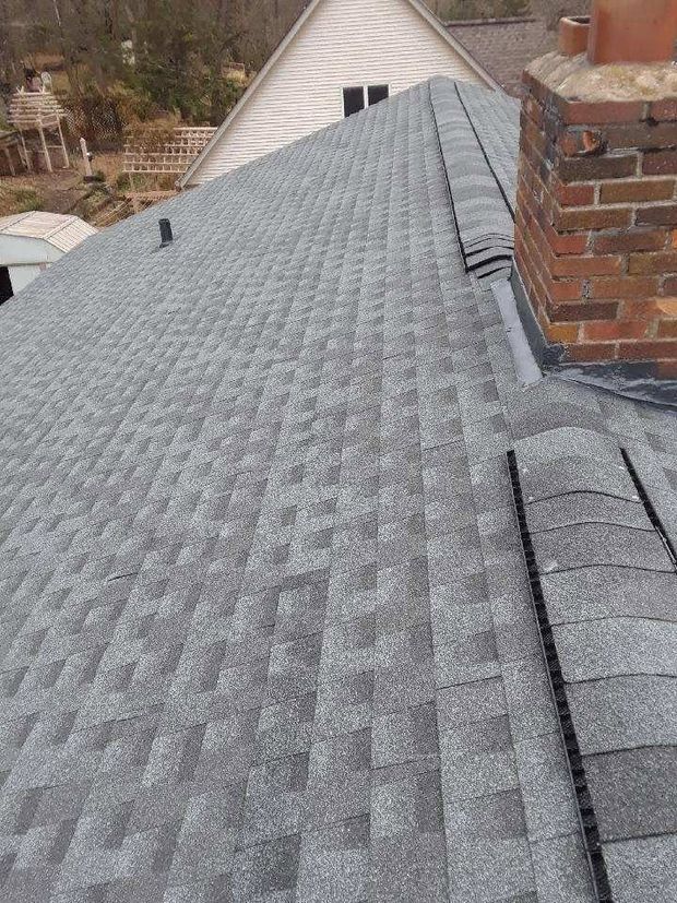 Gray shingled roof with a brick chimney and nearby house roofline