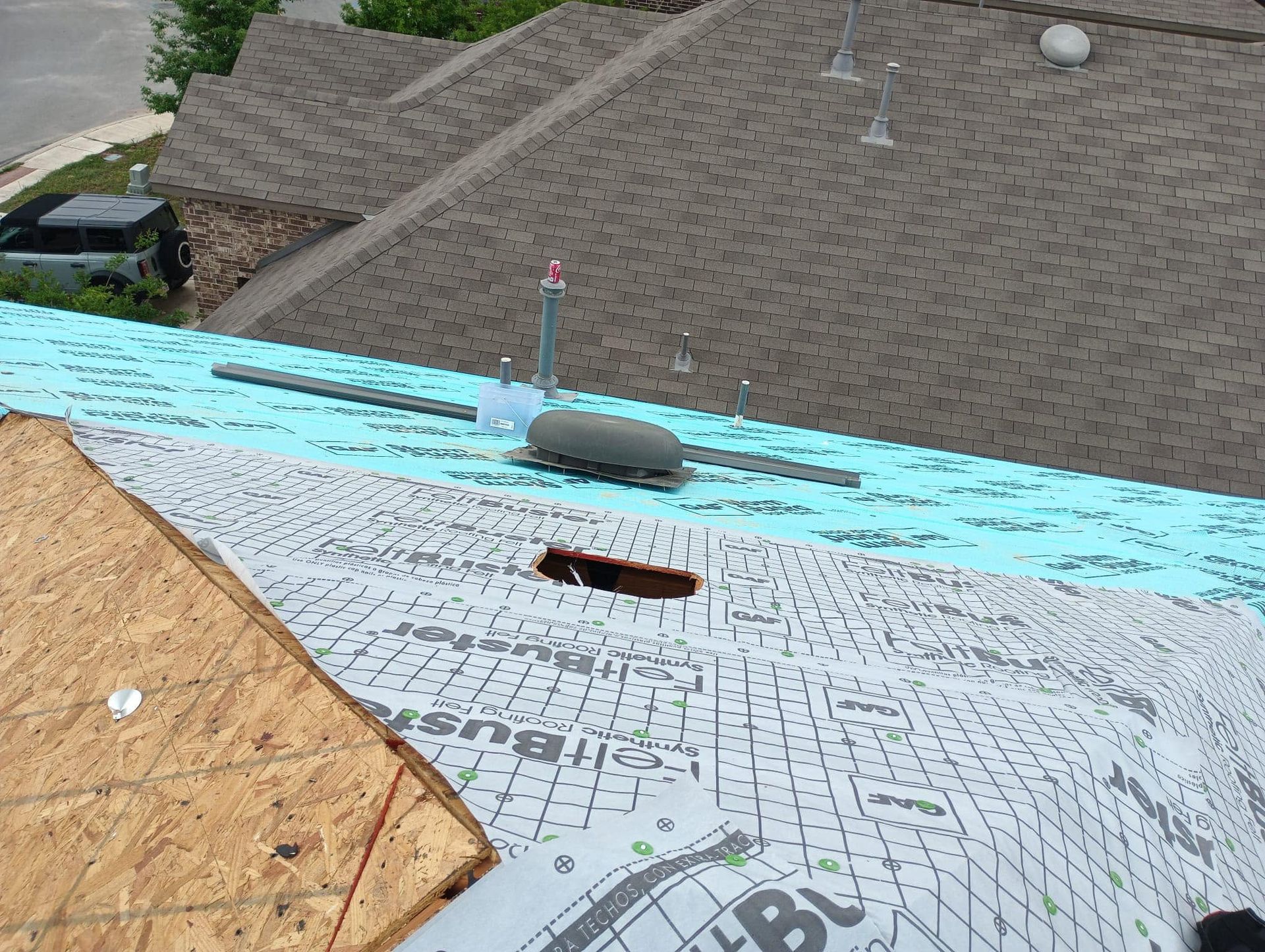 Roof with damaged shingles and a large hole near the ridge, shown in close-up.