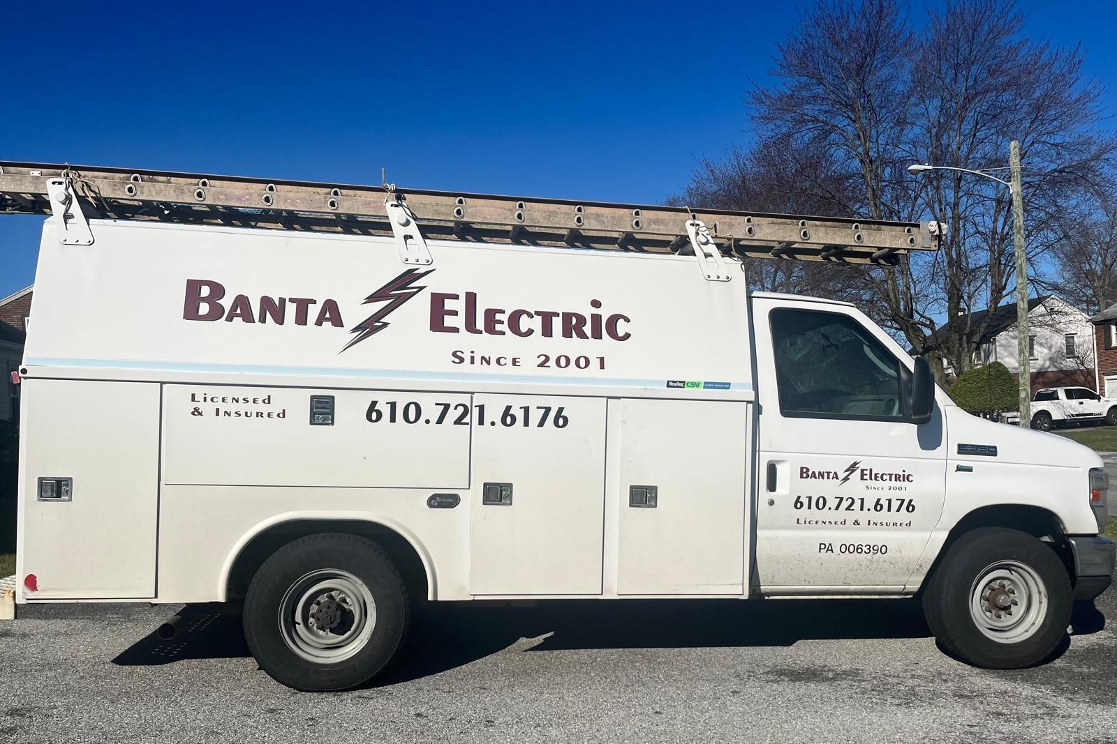 White Banta Electric service truck parked outdoors under a blue sky