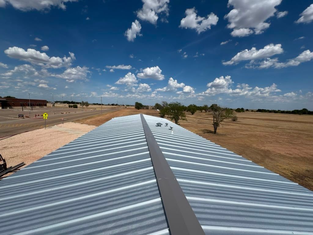 Long striped fabric laid across a dry field under a blue sky with scattered clouds
