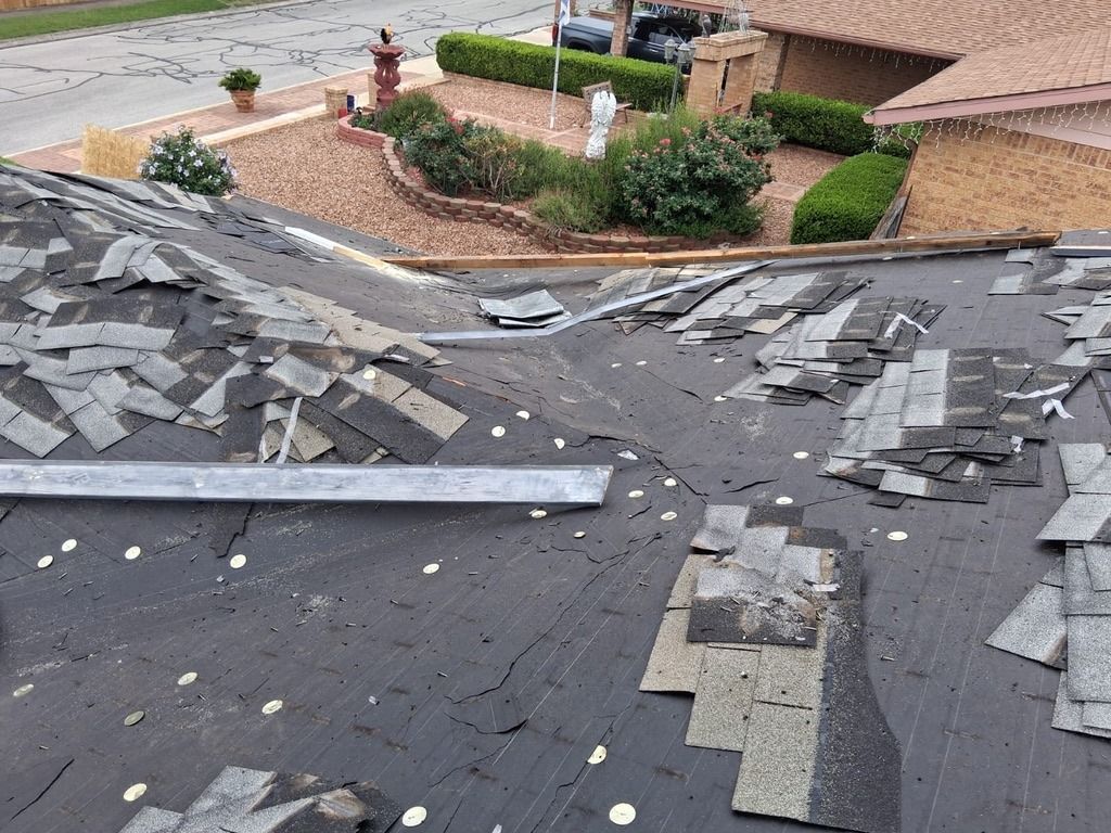 Damaged rooftop with missing shingles and debris, overlooking a suburban street and houses