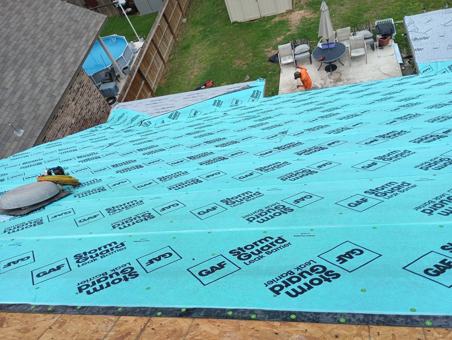 Turquoise roof under construction with workers and tools near a pool area