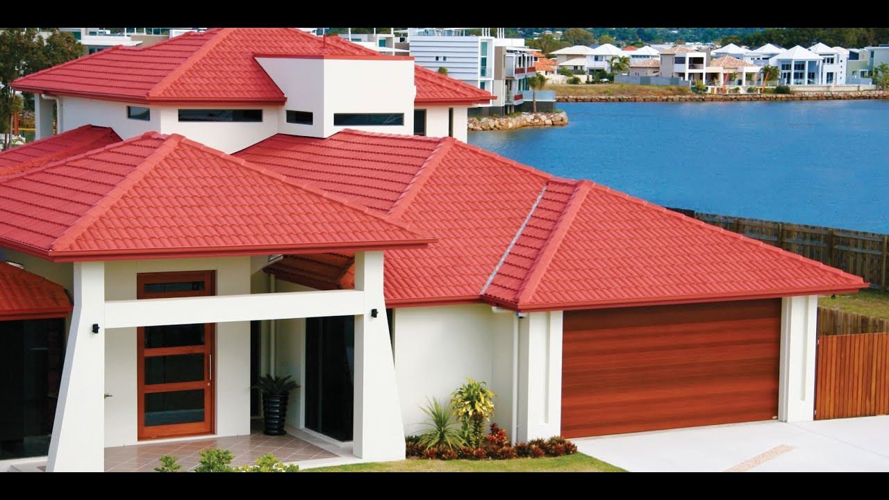 Modern white house with red tile roofs beside a calm blue waterfront