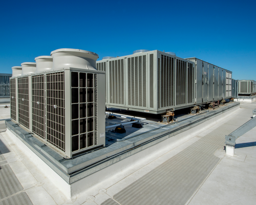 Rooftop HVAC units on a large commercial building under a clear sky