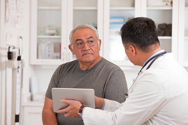 Doctor using digital tablet to talk to senior man