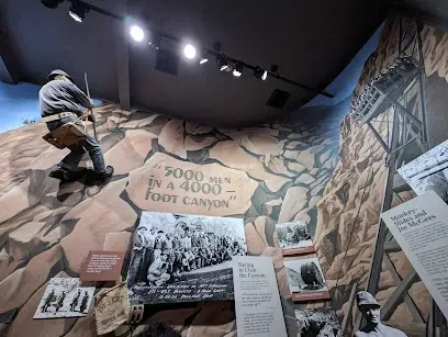 Mobile IVTherapyLas Vegas-Museum exhibit showing a mural of a canyon with a mannequin of a worker climbing rock faces. Text reads