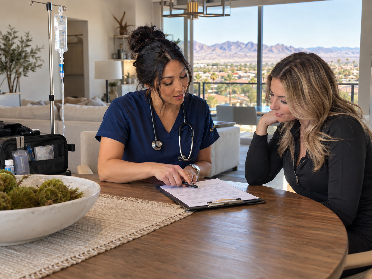 Two people reviewing paperwork at a round table in a bright office with mountain views.