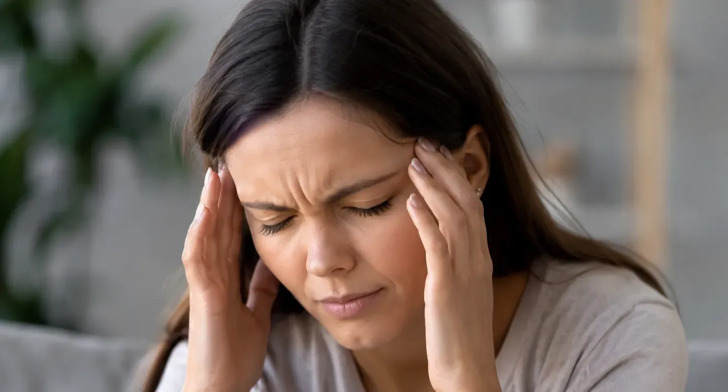 Person rubbing temples from a dehydration headache, highlighting symptoms that IV hydration therapy may help relieve.