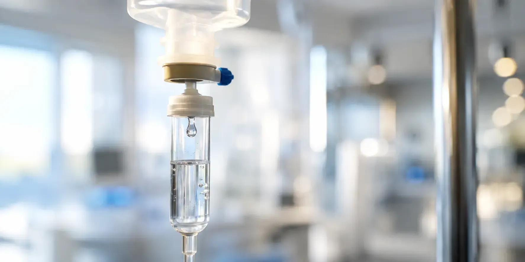 Close-up of clear IV fluid drops falling through a drip chamber, representing ReHydrate Drip hydration therapy.
