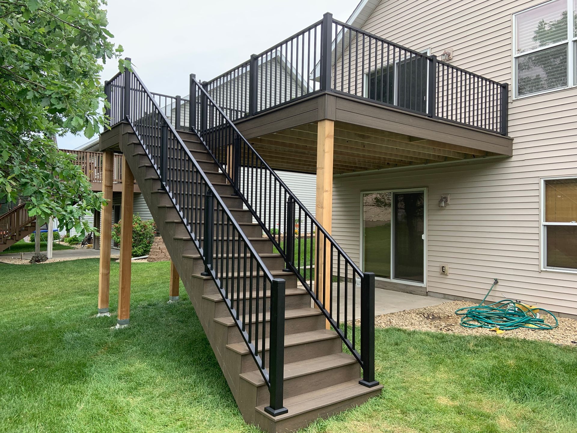 Exterior apartment stairway with black railings leading to an elevated deck over a grassy yard