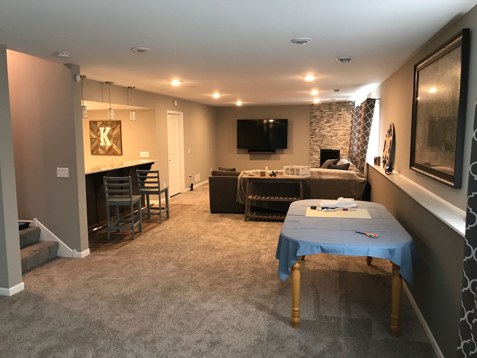 Spacious basement family room with carpet, sofa, TV, and a massage table near the foreground