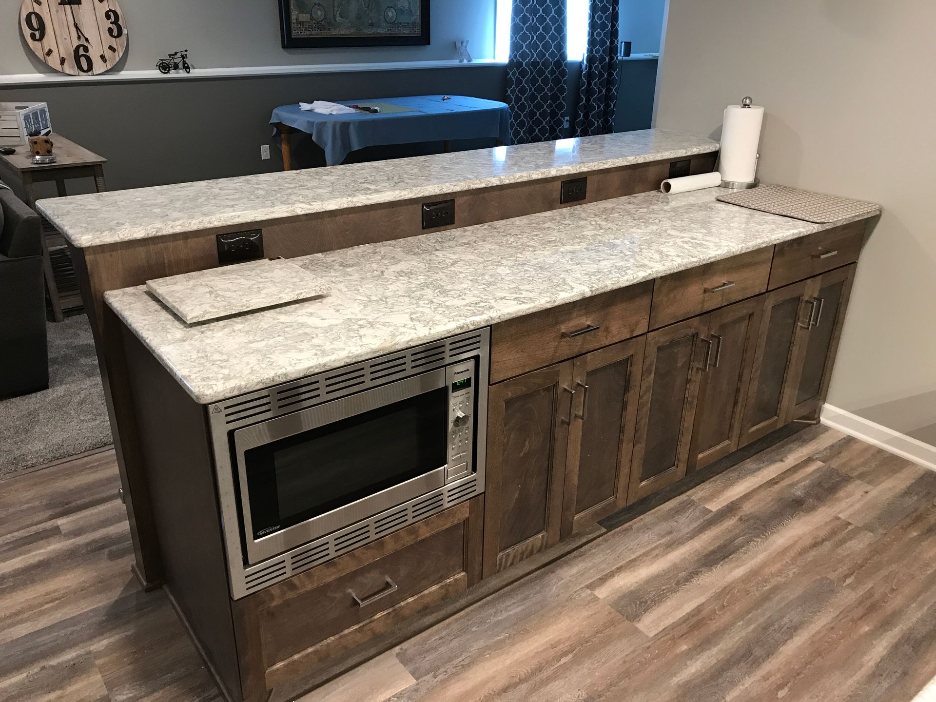 Kitchen island with speckled countertop, built-in microwave, and wood cabinets in a modern interior