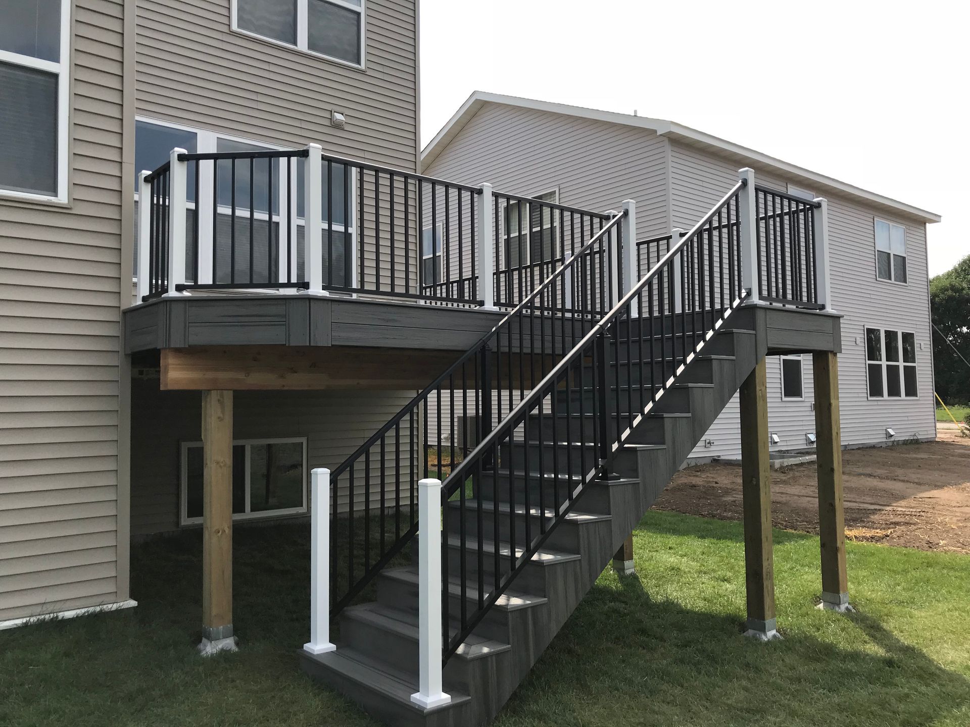 Back deck with black metal staircase and railing on a raised apartment building