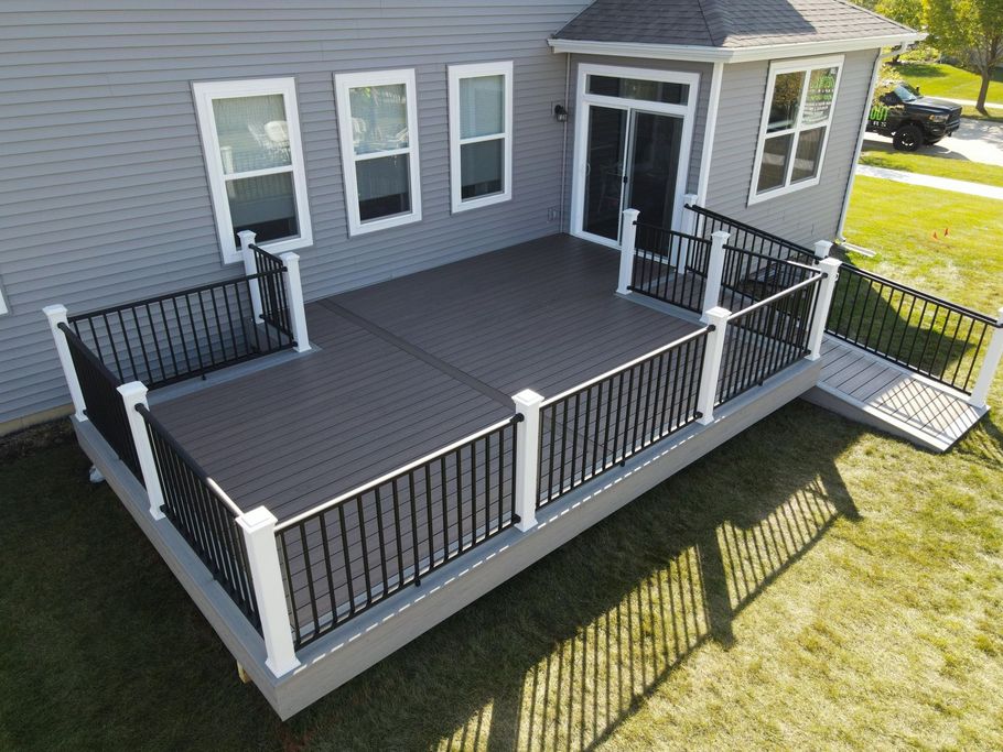 Gray house deck with black railings, white posts, and a small ramp leading to the yard