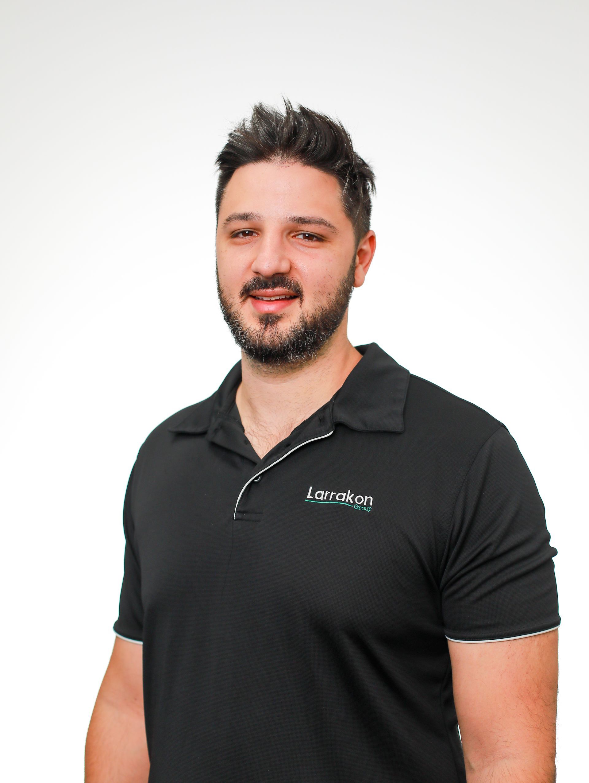 A man with a beard is wearing a black polo shirt