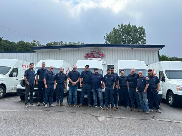 A group of men are posing for a picture in front of a building.