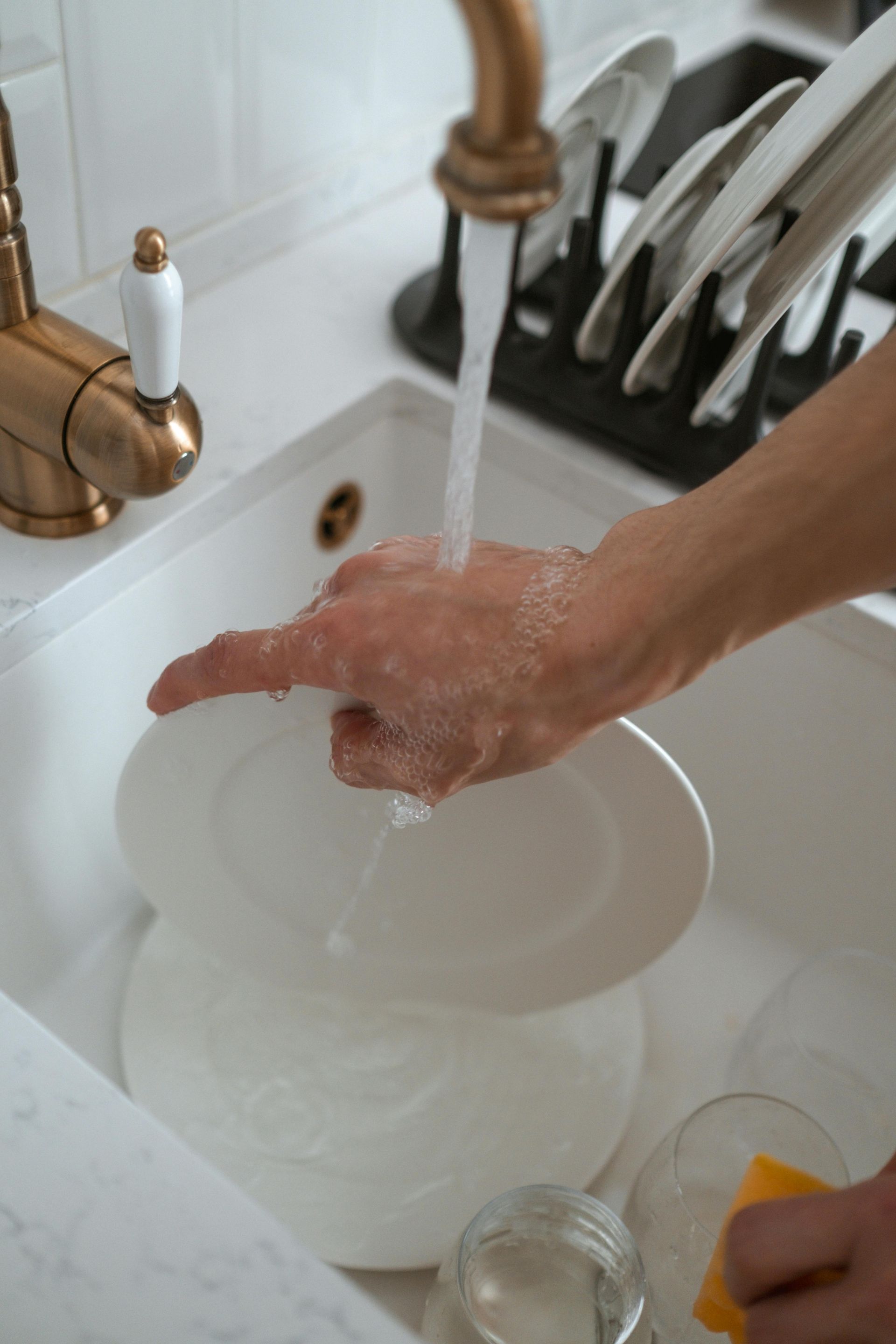 A person is washing a bowl in a kitchen sink.
