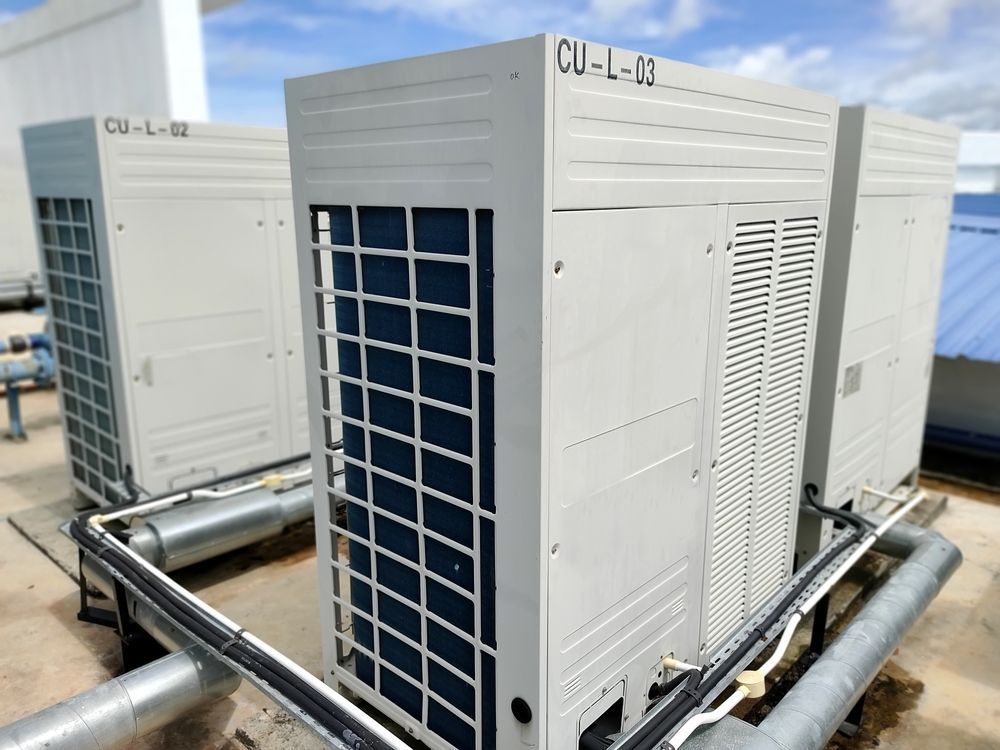 Outdoor HVAC condenser units with metal piping and vented panels on a rooftop platform
