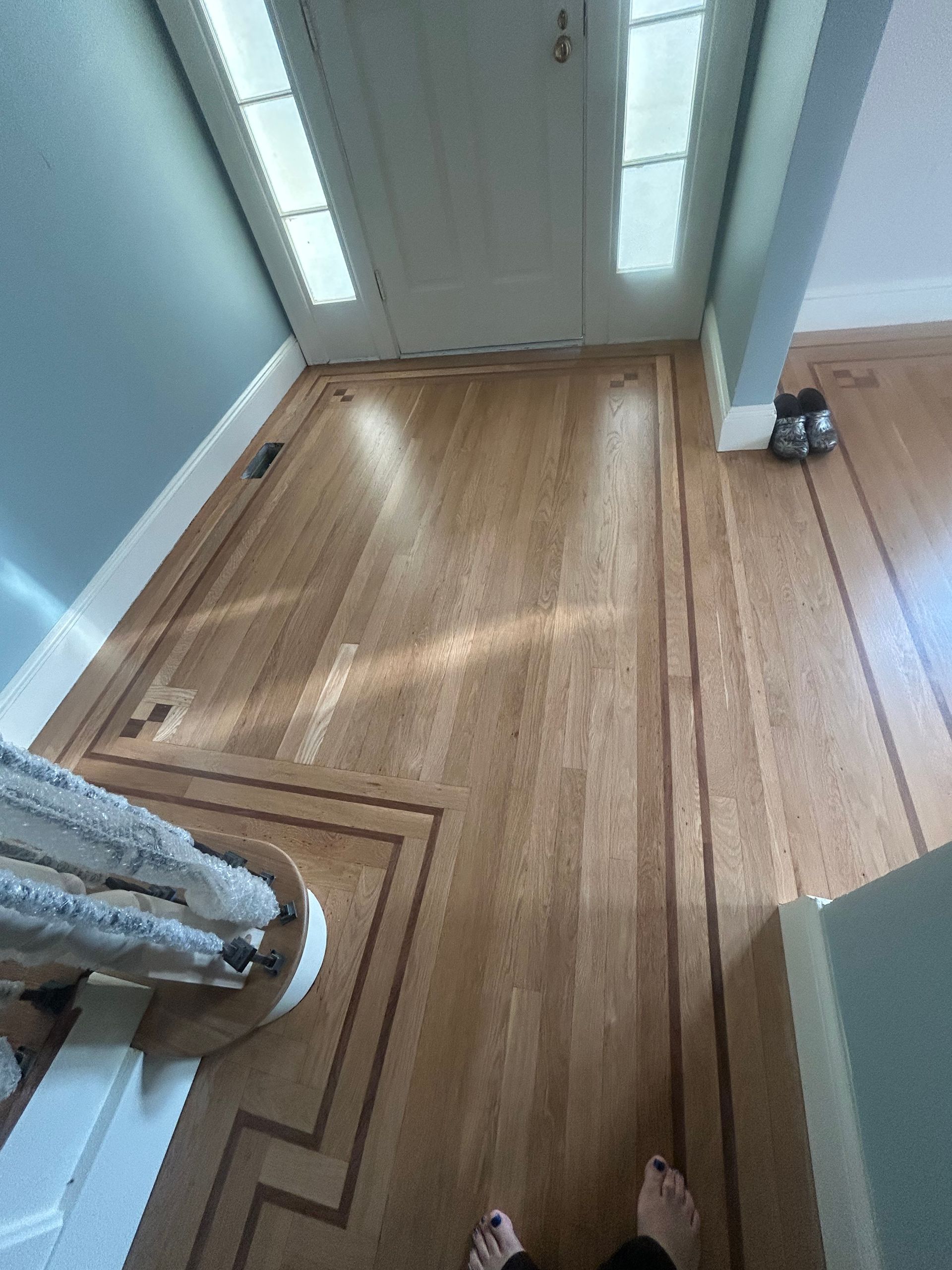 Wooden hallway with sunlit floorboards, blue walls, white doors, and a curtain at the left edge