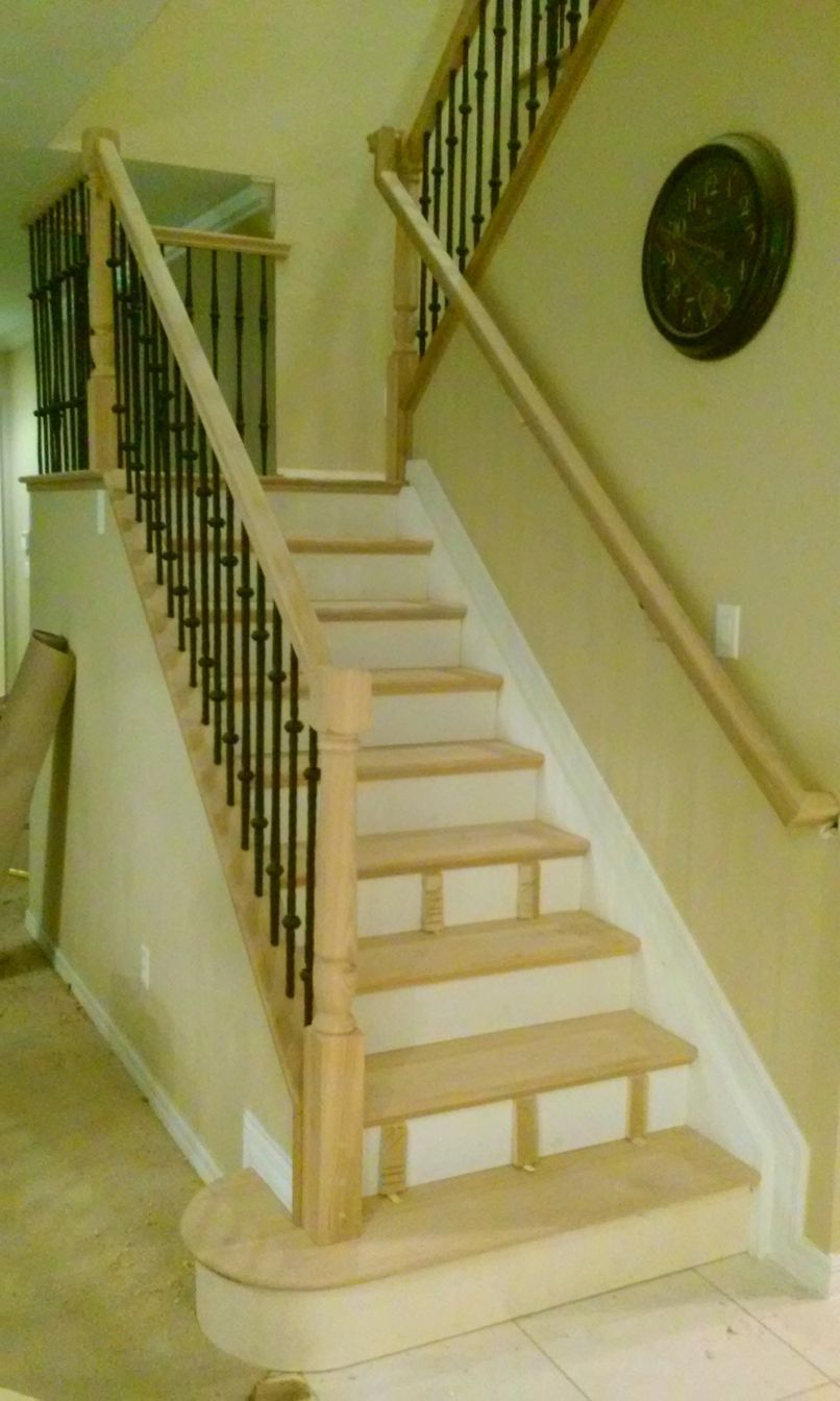 Indoor staircase with beige carpeted steps, dark wooden railing, and a round wall clock.
