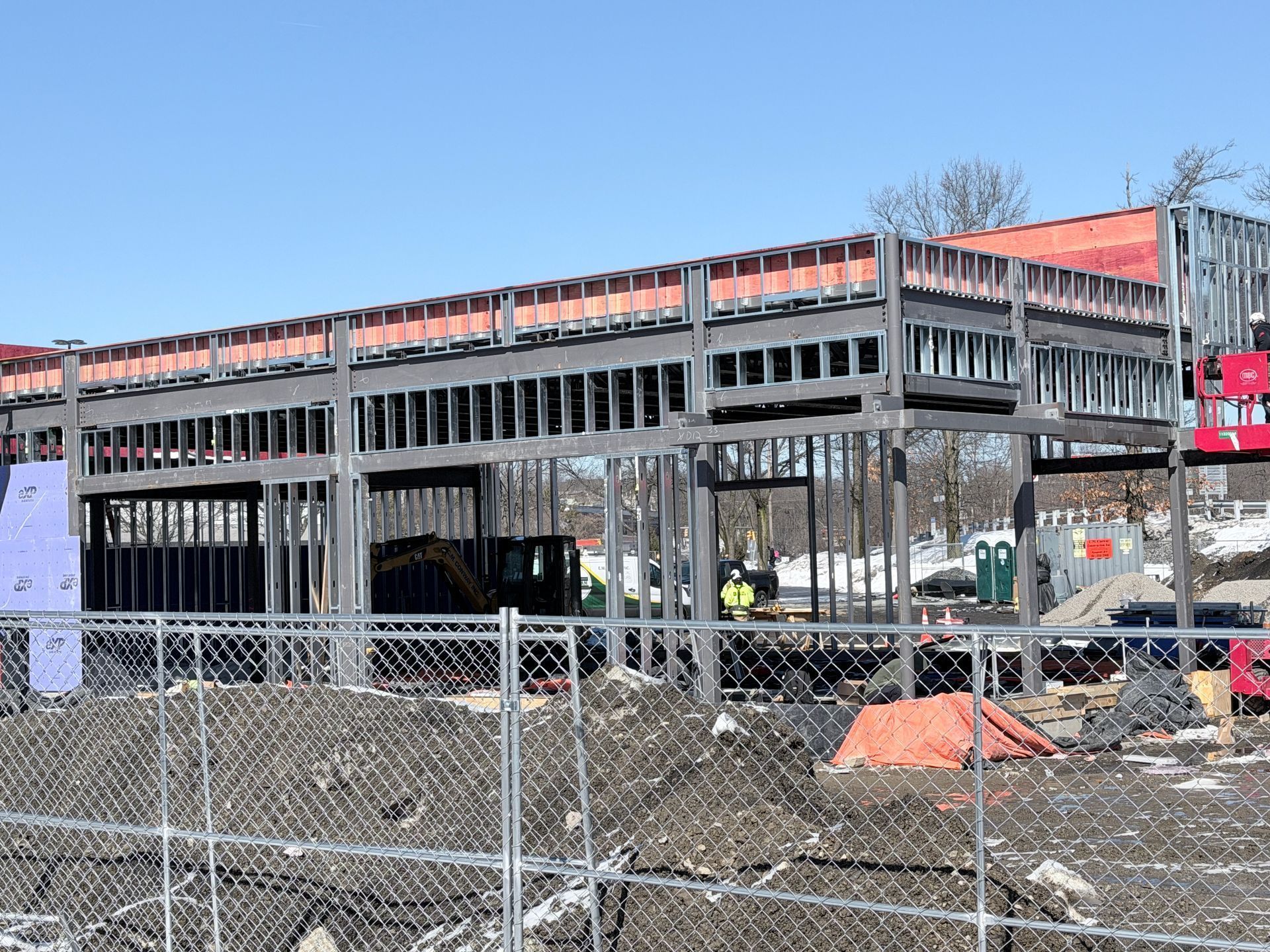 Partially built parking structure with chain-link fence and construction debris in front