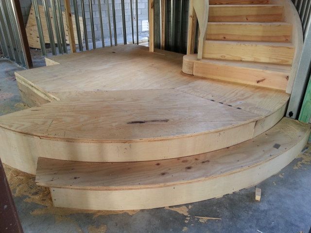 Curved wooden platform and steps under construction indoors