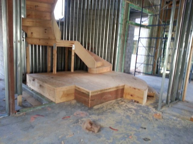 Unfinished wooden platform stage inside a framed room under construction