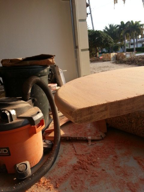 Orange vacuum and tan cushion on a porch with palm trees in the background